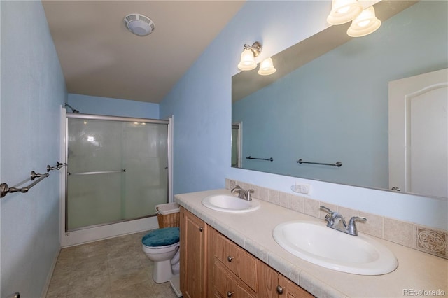 bathroom featuring a sink, a shower stall, toilet, and double vanity