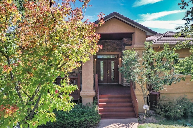 entrance to property featuring french doors, a tile roof, and stucco siding