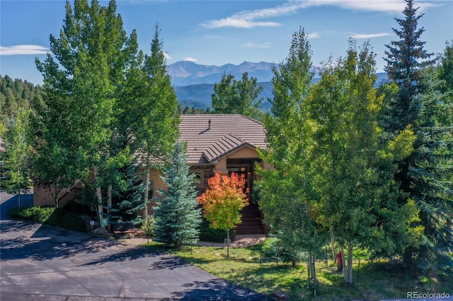 view of property hidden behind natural elements with a mountain view and a tile roof