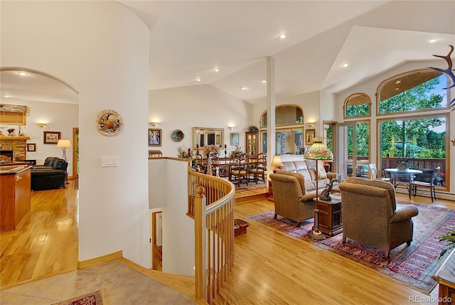 living room featuring high vaulted ceiling, arched walkways, and light wood-style floors