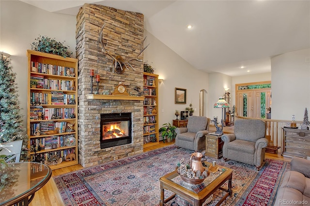 living room with arched walkways, a fireplace, recessed lighting, wood finished floors, and high vaulted ceiling