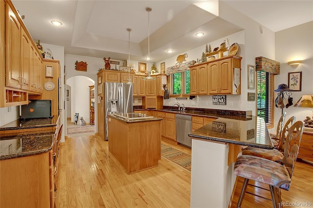 kitchen with a sink, a healthy amount of sunlight, arched walkways, and stainless steel appliances