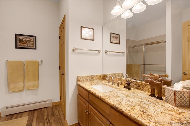full bathroom featuring vanity, an inviting chandelier, a stall shower, a baseboard radiator, and wood finished floors