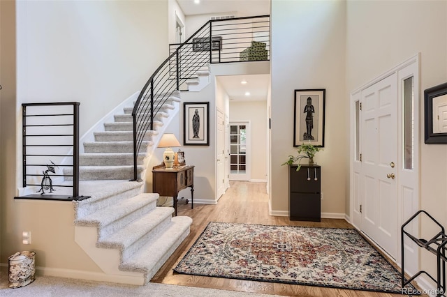 foyer featuring a towering ceiling and light hardwood / wood-style floors