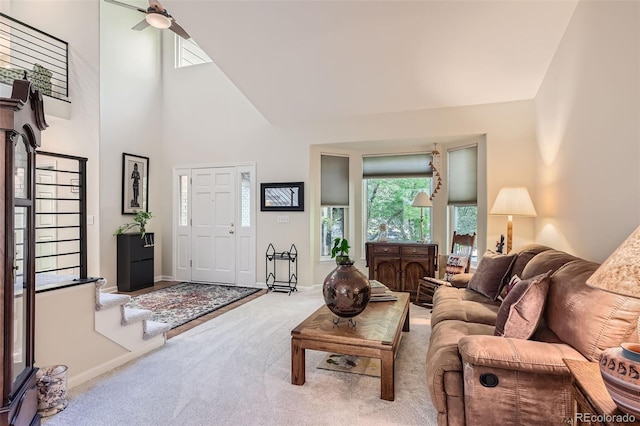 living room with a towering ceiling, carpet, and ceiling fan