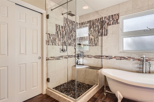 bathroom with hardwood / wood-style flooring, independent shower and bath, and tile walls