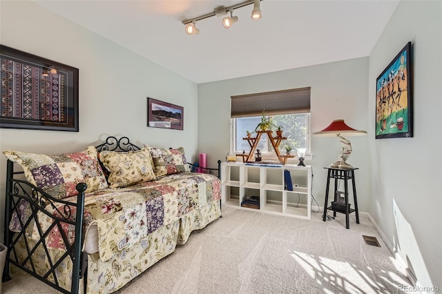 carpeted bedroom featuring track lighting