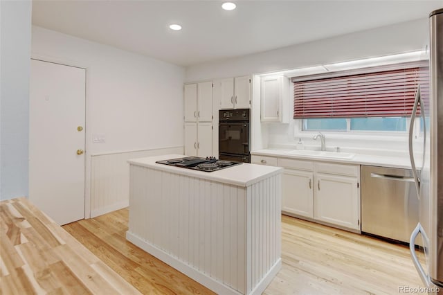 20 Scott Dr, Broomfield, CO 80020 - kitchen featuring a sink, black appliances, a wainscoted wall, white cabinets, and a center island