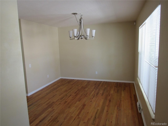 unfurnished room with dark wood-type flooring and a chandelier