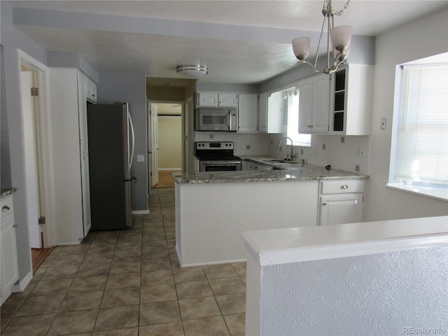 kitchen featuring appliances with stainless steel finishes, white cabinets, hanging light fixtures, and kitchen peninsula