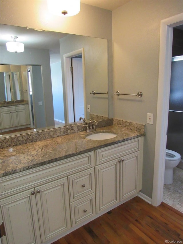 bathroom featuring toilet, hardwood / wood-style flooring, and vanity