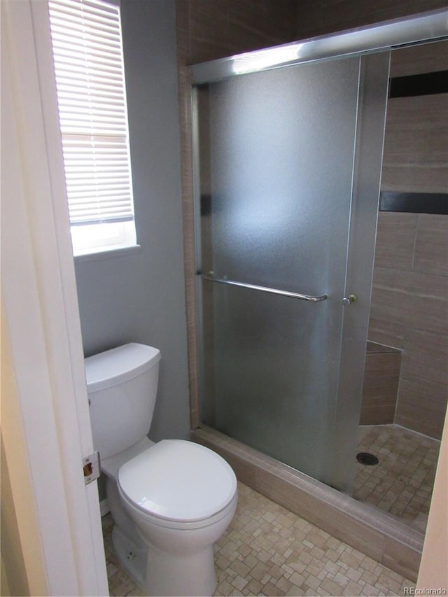 bathroom with toilet and a shower with shower door