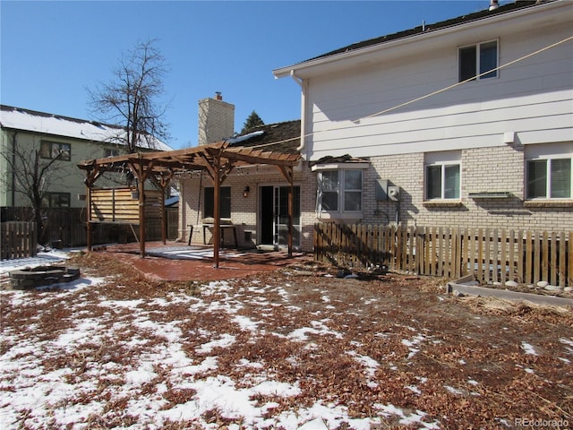 snow covered rear of property with a pergola