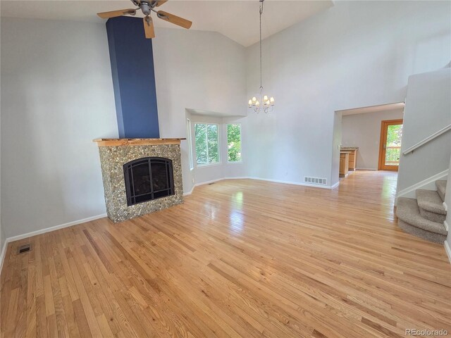 8772 S Carr Way, Littleton, CO 80128 - unfurnished living room featuring a chandelier, light wood finished floors, a fireplace, stairs, and ceiling fan