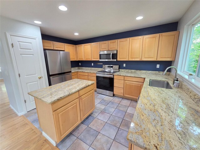 8772 S Carr Way, Littleton, CO 80128 - kitchen with stainless steel appliances, a sink, light brown cabinetry, light stone countertops, and a center island