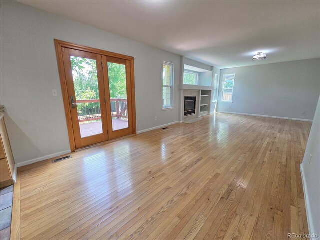 8772 S Carr Way, Littleton, CO 80128 - unfurnished living room featuring light wood-style flooring, baseboards, and a tile fireplace