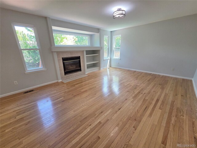 8772 S Carr Way, Littleton, CO 80128 - unfurnished living room featuring a fireplace, light wood finished floors, and baseboards