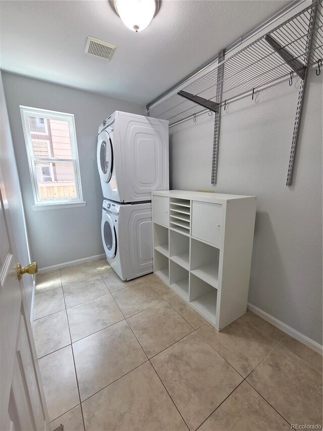 8772 S Carr Way, Littleton, CO 80128 - laundry area featuring stacked washing machine and dryer, baseboards, and light tile patterned floors