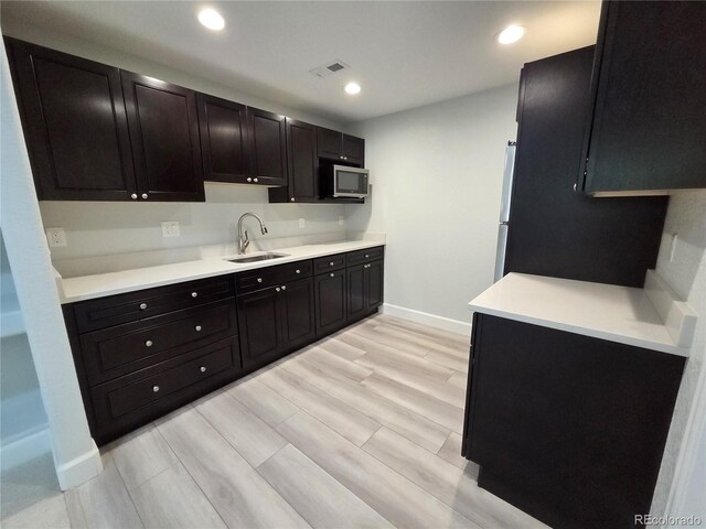 8772 S Carr Way, Littleton, CO 80128 - kitchen featuring a sink, stainless steel microwave, baseboards, light wood-type flooring, and light countertops