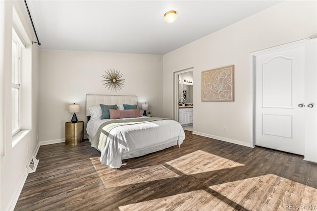 bedroom with multiple windows, dark hardwood / wood-style floors, and ensuite bathroom