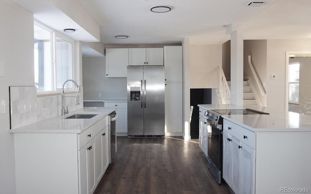 kitchen featuring sink, white cabinets, dark hardwood / wood-style floors, decorative backsplash, and stainless steel appliances