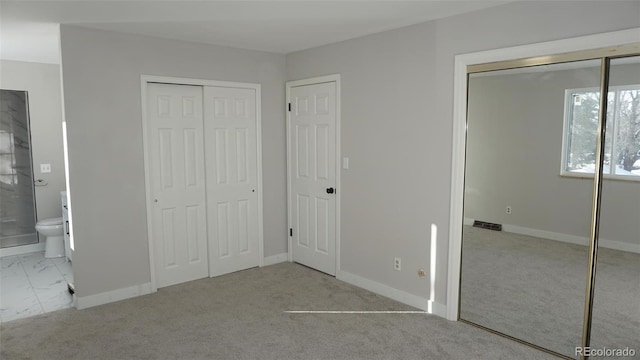 unfurnished bedroom featuring light carpet and ensuite bath