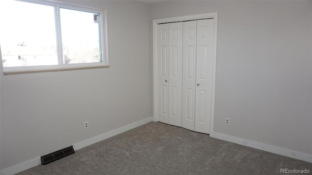 unfurnished bedroom featuring multiple windows, carpet flooring, and a closet