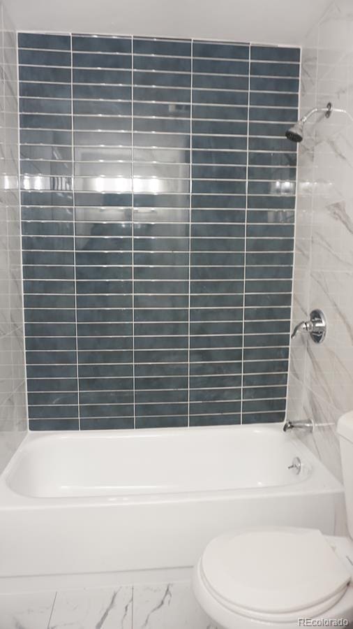 bathroom with toilet and tiled shower / bath