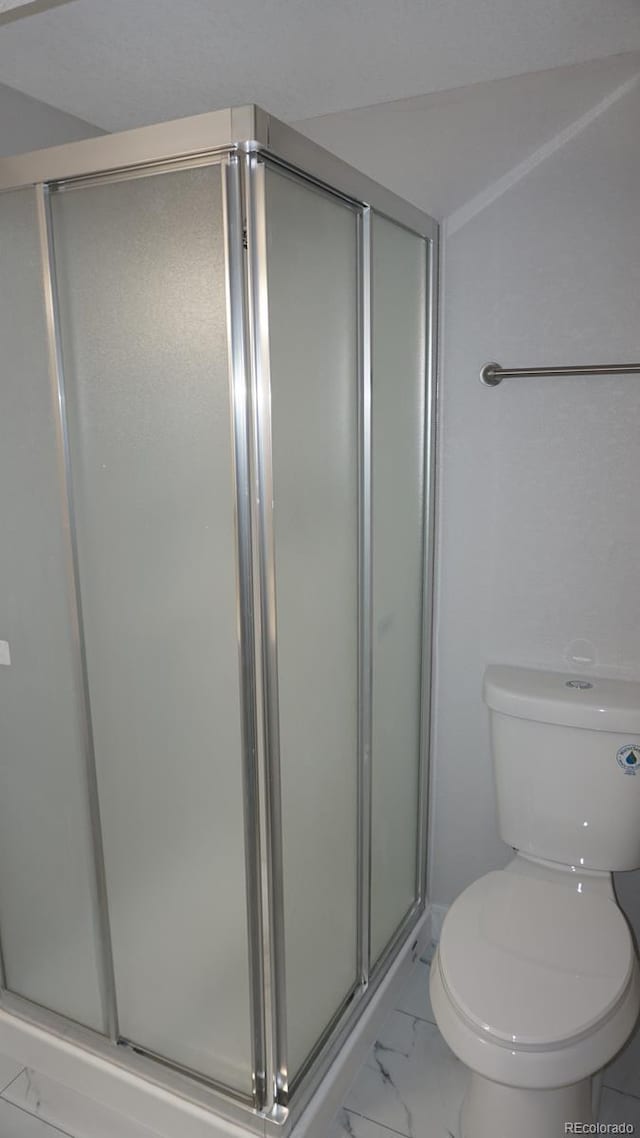 bathroom with a shower with door and toilet