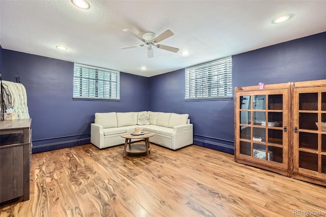 living area with a healthy amount of sunlight, ceiling fan, and wood finished floors
