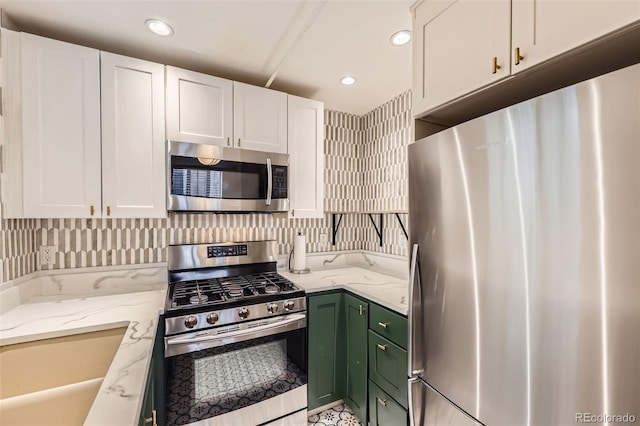 kitchen with white cabinets, appliances with stainless steel finishes, light stone counters, recessed lighting, and green cabinets
