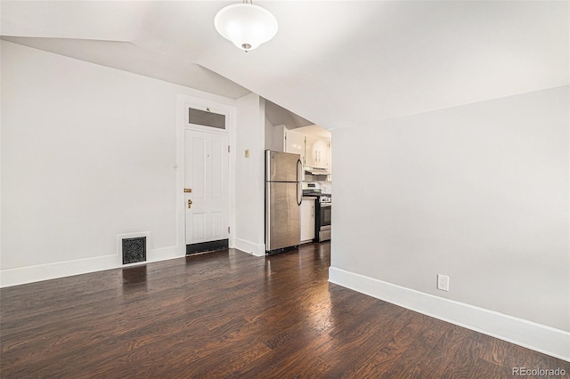 empty room featuring vaulted ceiling and dark wood-type flooring