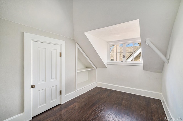 additional living space with dark hardwood / wood-style floors and built in features