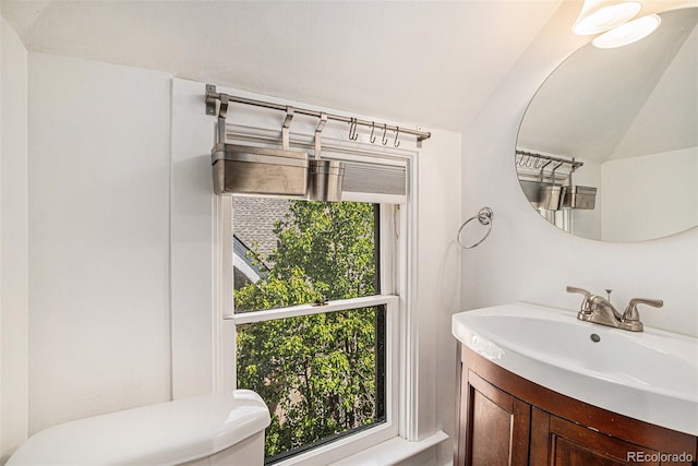 bathroom with vanity, lofted ceiling, and toilet