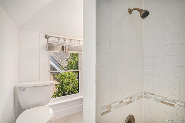 bathroom with tiled shower, a wealth of natural light, and toilet