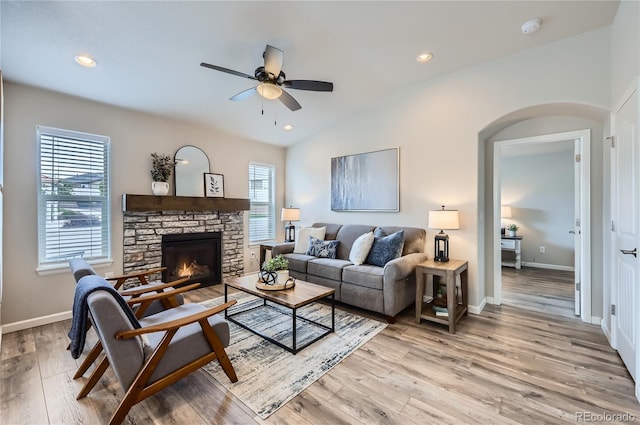 4318 Hessite Loop, Colorado Springs, CO 80938 - living room featuring a ceiling fan, light wood-type flooring, arched walkways, vaulted ceiling, and a stone fireplace