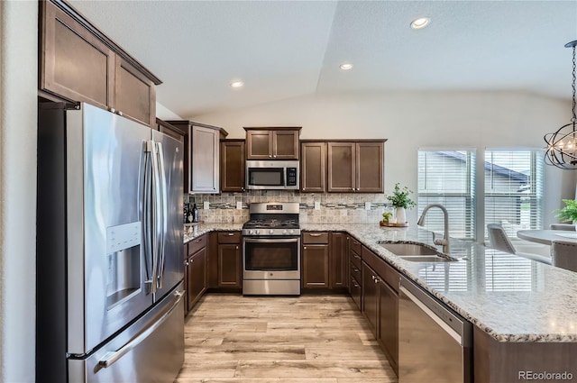 4318 Hessite Loop, Colorado Springs, CO 80938 - kitchen featuring appliances with stainless steel finishes, vaulted ceiling, a peninsula, light wood-style floors, and dark brown cabinetry