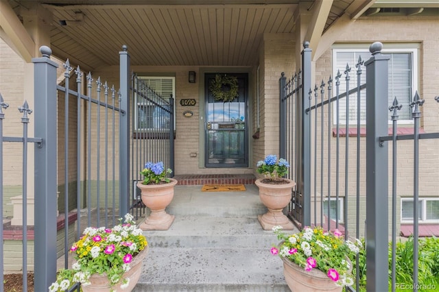 doorway to property featuring brick siding and a porch