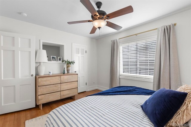 bedroom with wood finished floors, baseboards, and a ceiling fan