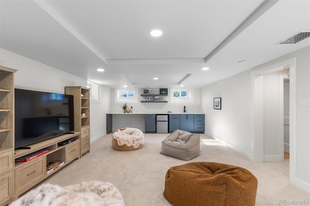 living room with light colored carpet, bar with sink, recessed lighting, and baseboards
