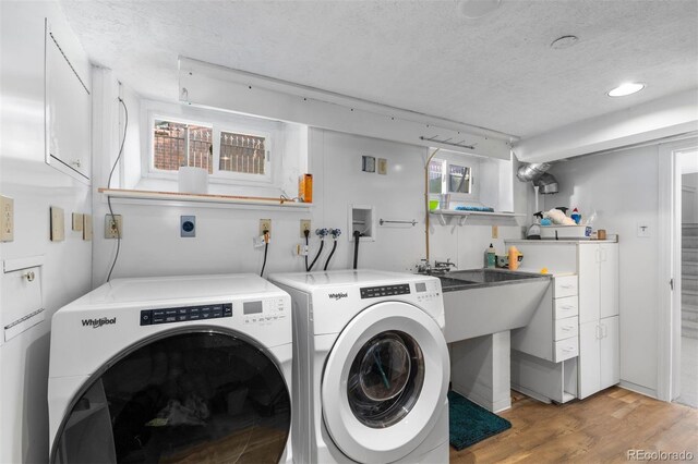 laundry room with a textured ceiling, light wood finished floors, and washing machine and dryer