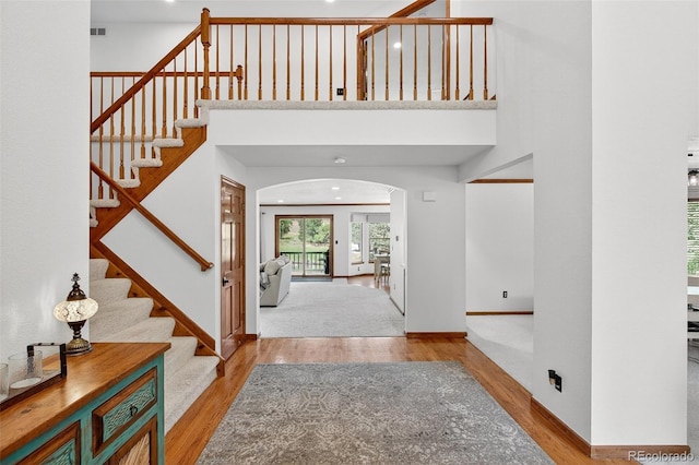 1 Amaranth Dr, Littleton, CO 80127 - entrance foyer with arched walkways, wood finished floors, stairs, and a towering ceiling