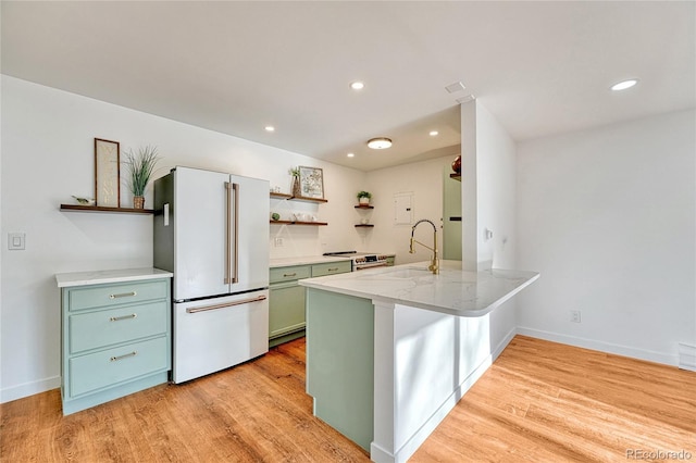 kitchen with stainless steel range with electric cooktop, sink, light wood-type flooring, high end fridge, and kitchen peninsula