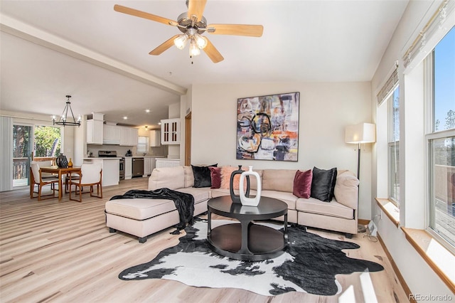 living room with ceiling fan with notable chandelier, vaulted ceiling, and light hardwood / wood-style flooring