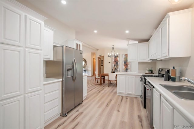 kitchen featuring appliances with stainless steel finishes, light hardwood / wood-style floors, white cabinetry, and an inviting chandelier