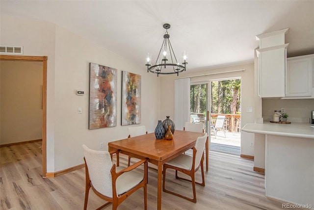 dining space with a notable chandelier, light hardwood / wood-style flooring, and vaulted ceiling