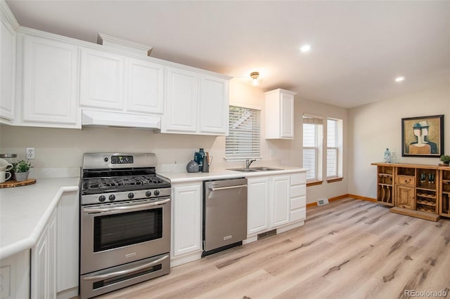 kitchen with white cabinetry, stainless steel appliances, light wood-type flooring, custom exhaust hood, and sink