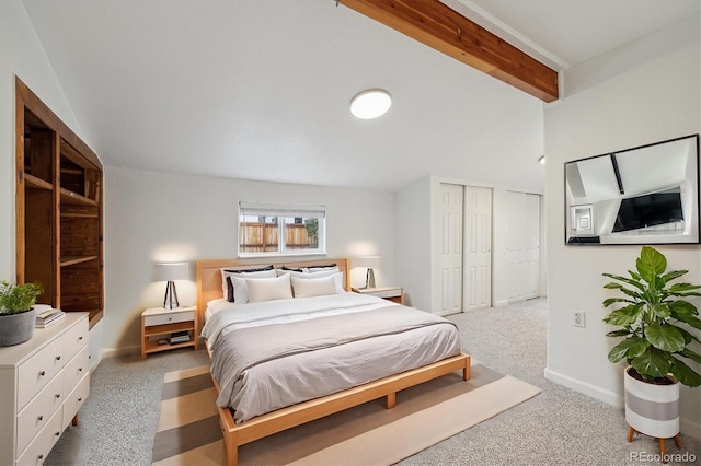 carpeted bedroom with beam ceiling and multiple closets