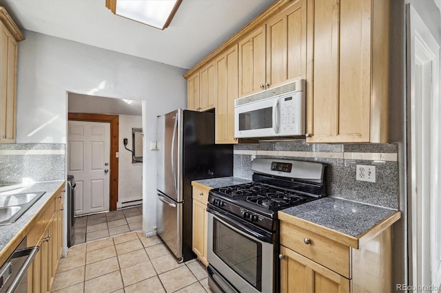 kitchen with decorative backsplash, baseboard heating, light tile patterned flooring, appliances with stainless steel finishes, and light brown cabinetry