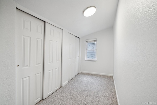 unfurnished bedroom with light colored carpet and lofted ceiling